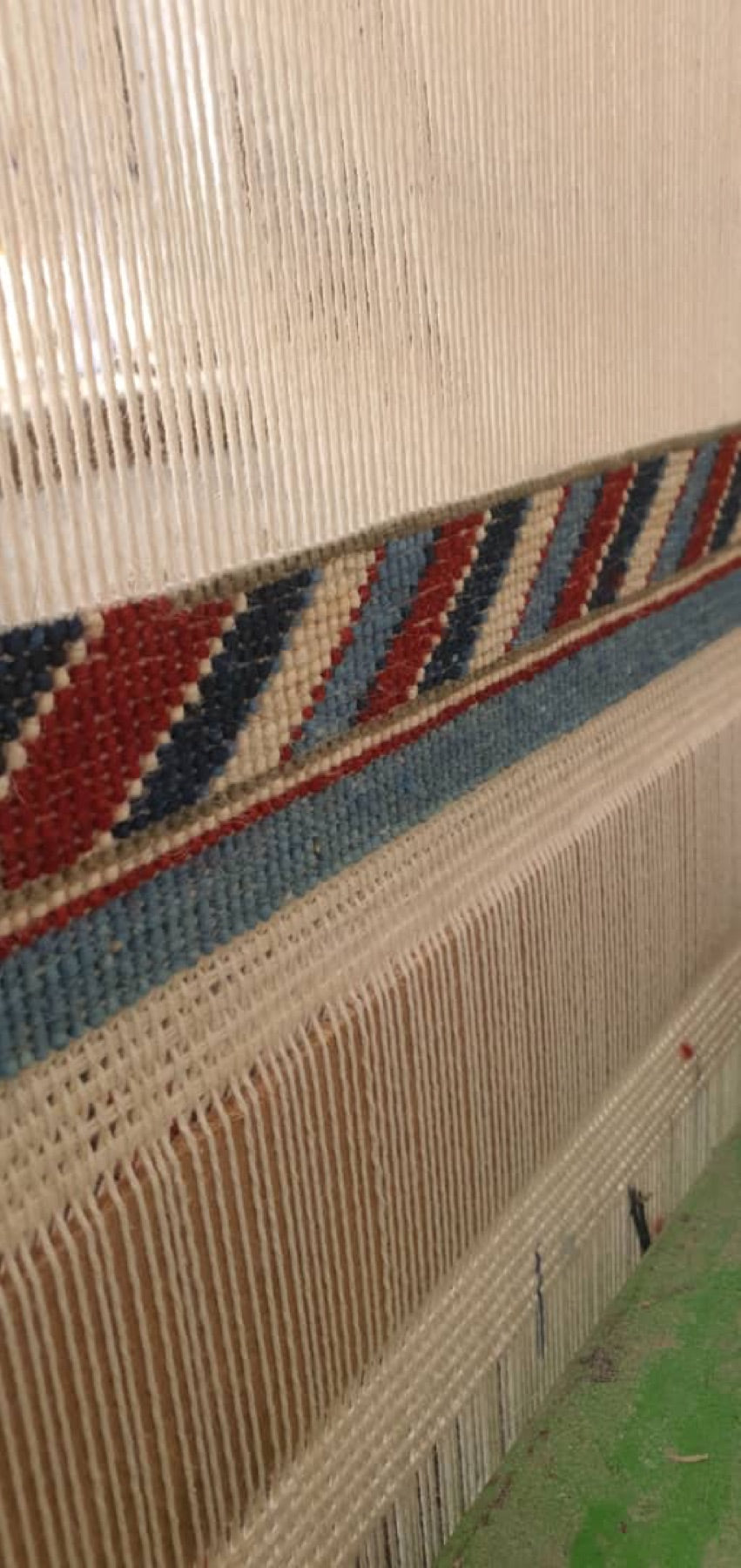Cotton warp threads and the first rows of a hand-knotted rug on the loom