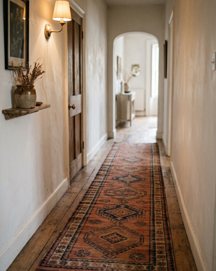 Kilim runner rug in terracotta and indigo running down a warm plaster hallway